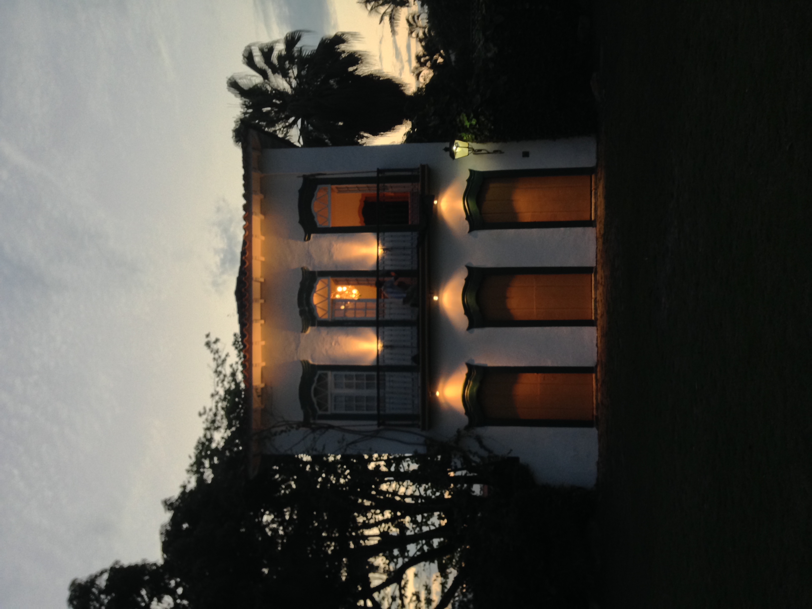 Colonial Brazilian house at dusk, warm light from windows, figure on balcony